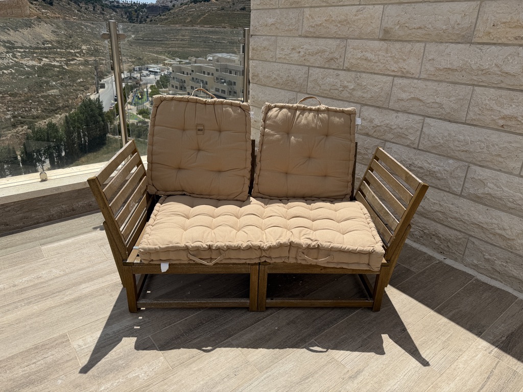 מהפכת הווידאו באיקומרס: כיצד שילוב סרטונים קצרים בדפי מוצר וקטגוריות מזניק את ה-ROI ספסל עץ לגינה עם כריות בז' על מרפסת — תמונת המוצר הסטטית המקורית שהועלתה למערכת